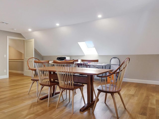 dining space with a skylight, baseboards, lofted ceiling, light wood-style floors, and recessed lighting