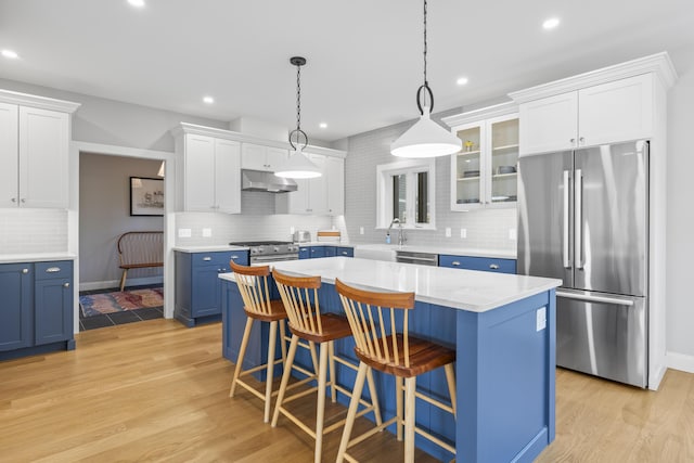92 Brooks Cove Rd, Westport Island, ME 04578 - kitchen featuring premium appliances, blue cabinetry, under cabinet range hood, tasteful backsplash, and white cabinets