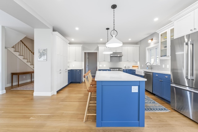 92 Brooks Cove Rd, Westport Island, ME 04578 - kitchen featuring appliances with stainless steel finishes, blue cabinetry, under cabinet range hood, a center island, and light countertops