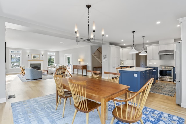 92 Brooks Cove Rd, Westport Island, ME 04578 - dining area with stairway, a fireplace, light wood-style floors, recessed lighting, and a chandelier