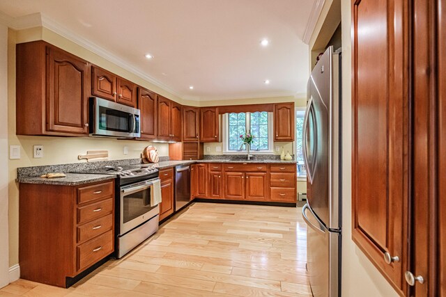 55 Evergreen Ln, Windham, ME 04062 - kitchen with appliances with stainless steel finishes, crown molding, light wood-type flooring, a sink, and dark stone counters