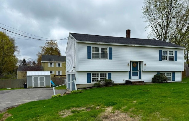 split foyer home with a shed, a chimney, and an outbuilding