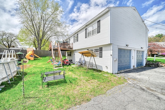 view of property exterior with a garage, a playground, asphalt driveway, a deck, and stairs
