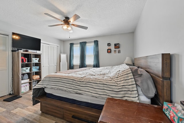 bedroom featuring light wood-type flooring, a textured ceiling, and ceiling fan
