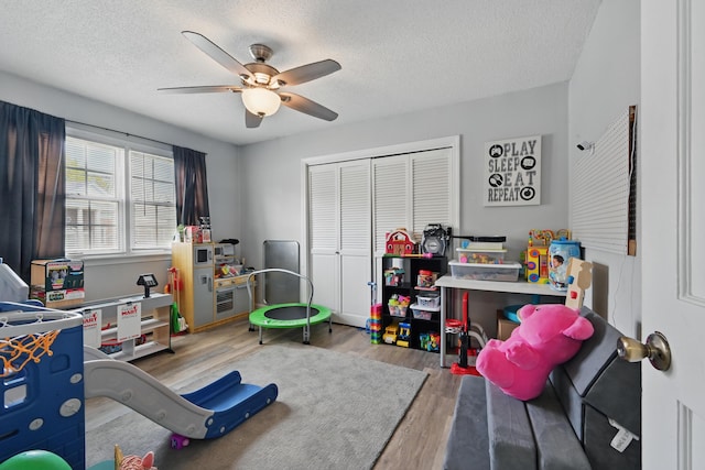 playroom featuring wood finished floors, a ceiling fan, and a textured ceiling