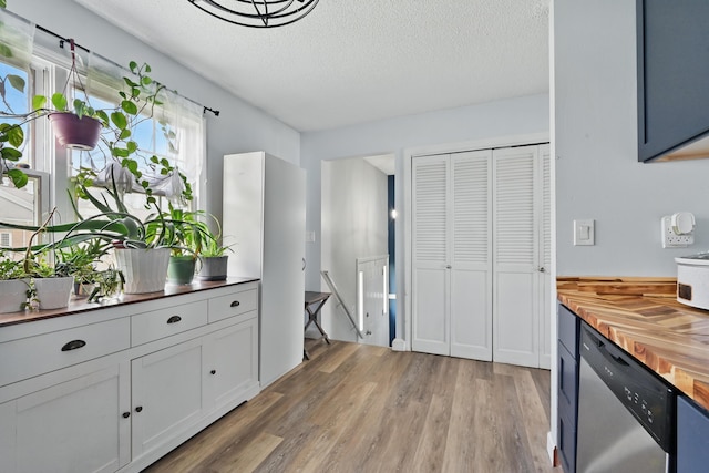kitchen with wood counters, dishwasher, light wood-style floors, a textured ceiling, and white cabinetry
