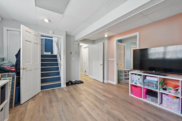 rec room with a drop ceiling, wood finished floors, and baseboards