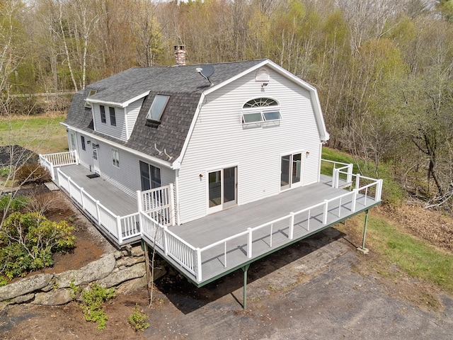 289 W Washington Rd, Washington, ME 04574 - back of property with roof with shingles, a wooden deck, a gambrel roof, a chimney, and a forest view
