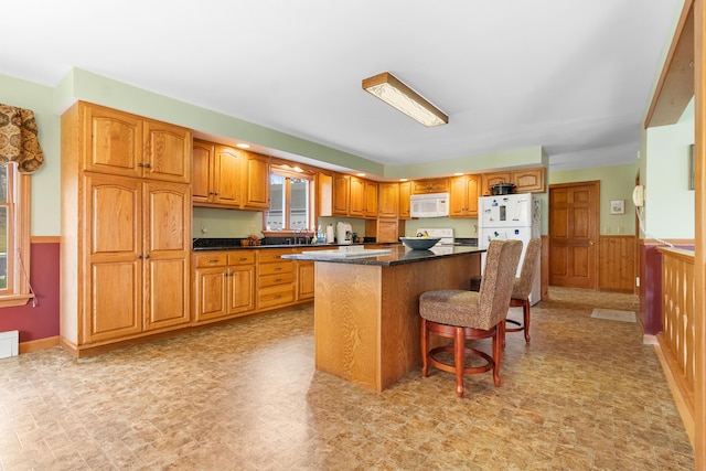 289 W Washington Rd, Washington, ME 04574 - kitchen with white appliances, a center island, wainscoting, a breakfast bar area, and brown cabinets