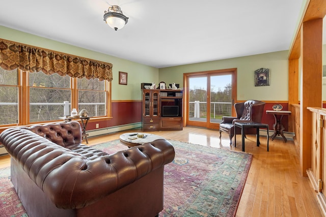 289 W Washington Rd, Washington, ME 04574 - living room with a baseboard heating unit, a wainscoted wall, and light wood-style flooring