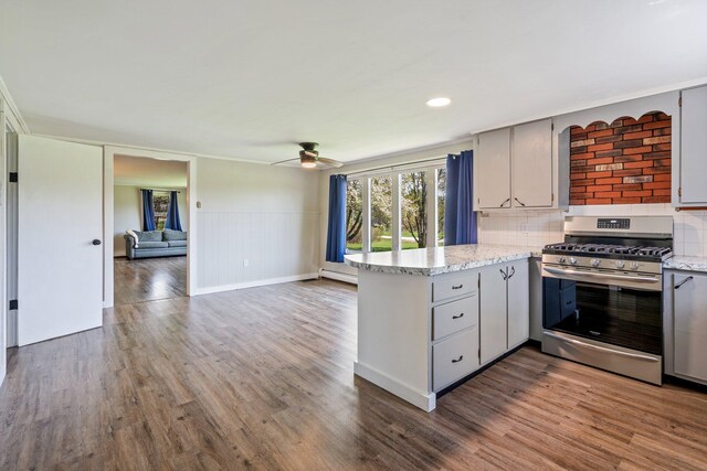 7 Hubbard Ave, Limington, ME 04049 - kitchen with stainless steel gas stove, a peninsula, gray cabinetry, baseboard heating, and a wainscoted wall