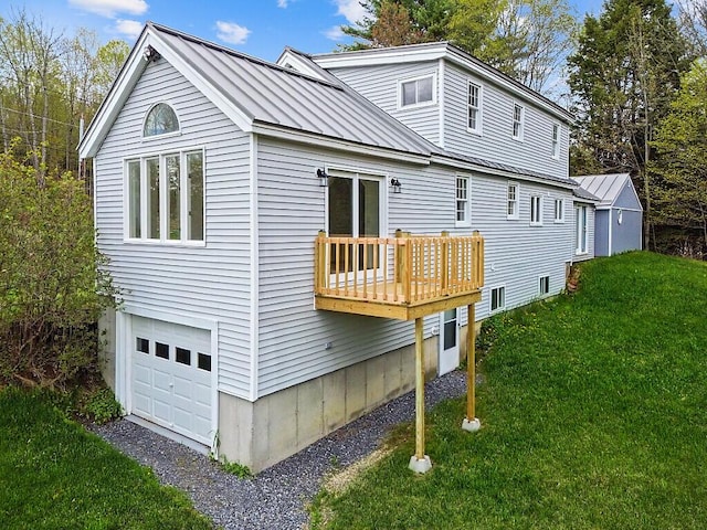 rear view of property with an attached garage, a yard, a standing seam roof, and metal roof