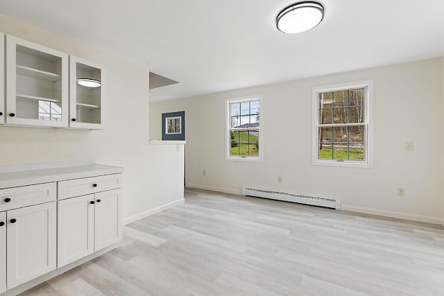 unfurnished living room featuring baseboard heating, light wood-style flooring, and baseboards