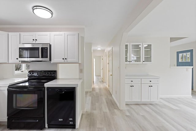 kitchen with stainless steel microwave, black / electric stove, and white cabinetry