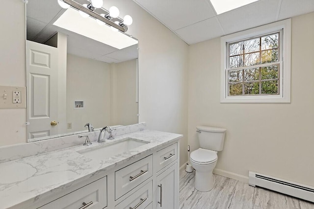 bathroom featuring a baseboard heating unit, baseboards, toilet, and vanity