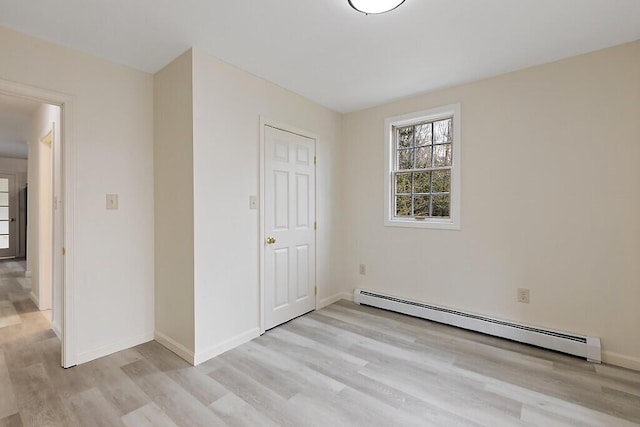 unfurnished bedroom with baseboard heating, light wood-type flooring, and baseboards