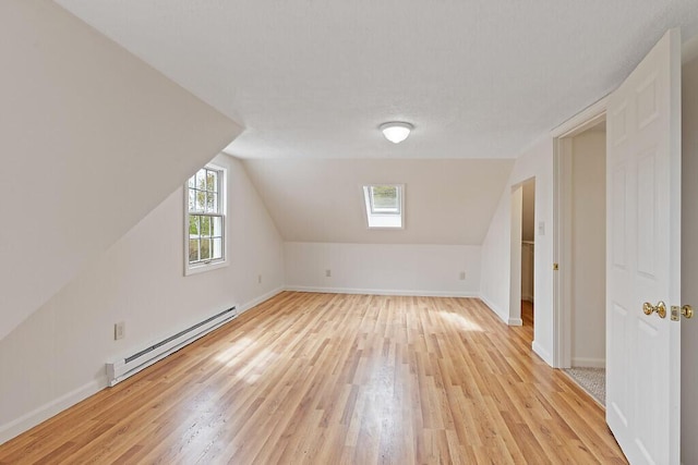 additional living space with baseboard heating, light wood-type flooring, baseboards, and vaulted ceiling