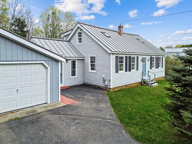 view of front of home featuring a standing seam roof, entry steps, a chimney, metal roof, and a front yard