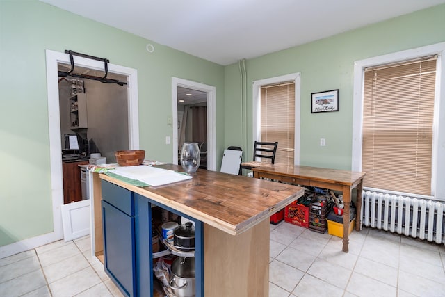 kitchen with radiator heating unit, wood counters, light tile patterned floors, blue cabinets, and a center island