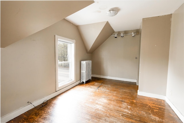 additional living space featuring radiator, lofted ceiling, hardwood / wood-style floors, and baseboards