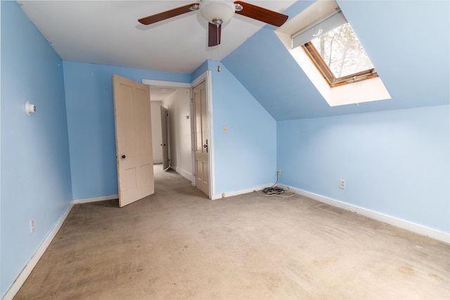 additional living space with lofted ceiling, ceiling fan, light carpet, a skylight, and baseboards