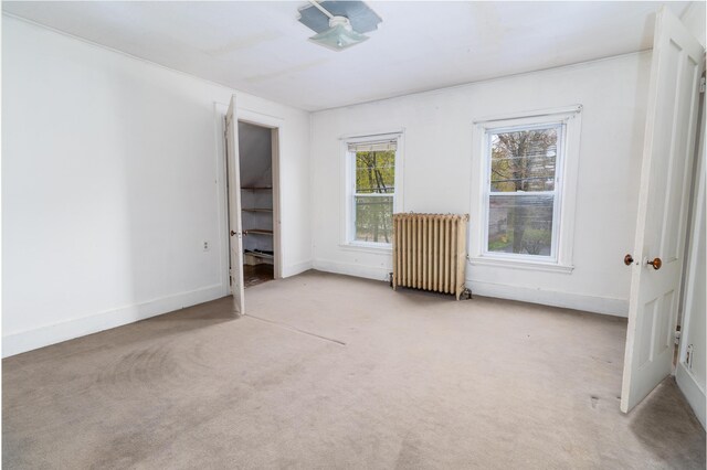 unfurnished bedroom featuring radiator, carpet floors, and baseboards