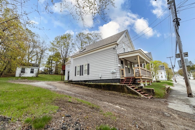 view of property exterior featuring dirt driveway, a yard, stairs, and an outbuilding