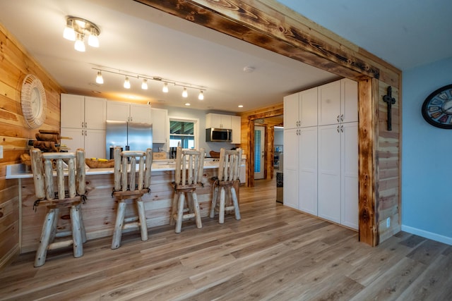 50 Beans Mill Rd, Corinth, ME 04427 - kitchen with stainless steel appliances, white cabinetry, light wood-style flooring, a breakfast bar, and light countertops