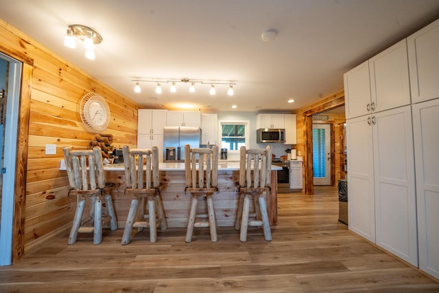 50 Beans Mill Rd, Corinth, ME 04427 - kitchen with stainless steel appliances, light wood-style floors, white cabinetry, wood walls, and recessed lighting