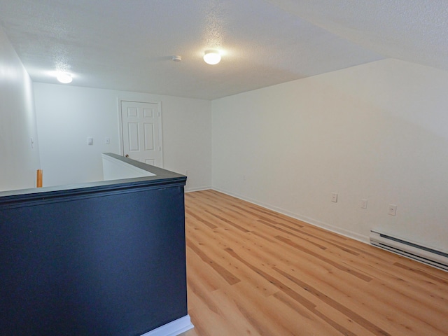 35 Mathews Ave Unit 8, Waterville, ME 04901 - empty room with light wood finished floors, baseboard heating, a textured ceiling, baseboards, and lofted ceiling