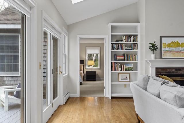49 Dipper Cove Rd, Harpswell, ME 04066 - living area with vaulted ceiling, light wood finished floors, a baseboard heating unit, and a brick fireplace