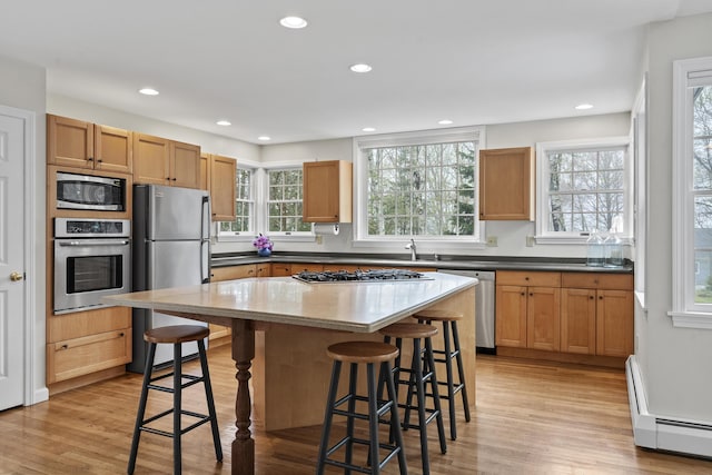 49 Dipper Cove Rd, Harpswell, ME 04066 - kitchen with stainless steel appliances, a baseboard heating unit, a breakfast bar, recessed lighting, and light wood-style flooring
