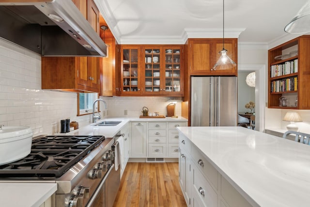 31 Mackworth St, Portland, ME 04103 - kitchen with stainless steel appliances, under cabinet range hood, a sink, light countertops, and glass insert cabinets
