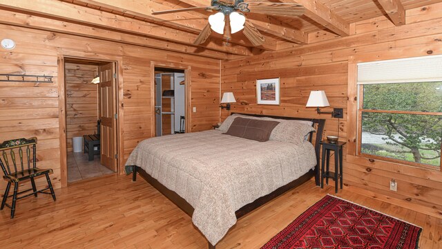 bedroom featuring beam ceiling, wood walls, and light wood finished floors