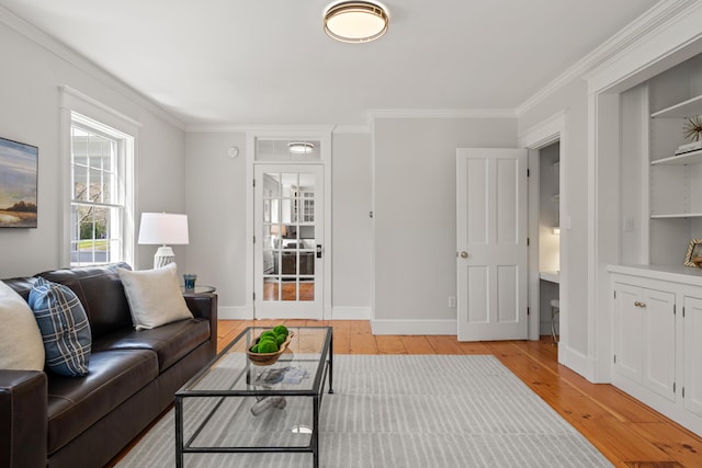 living room featuring light wood-type flooring, crown molding, and baseboards