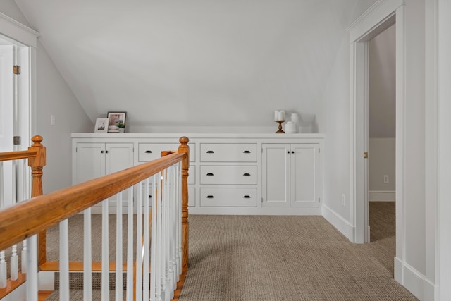 hallway with vaulted ceiling, an upstairs landing, carpet, and baseboards