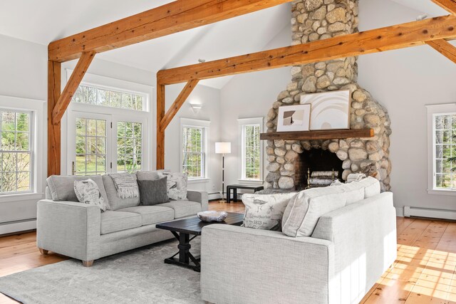 living room featuring hardwood / wood-style flooring, a baseboard heating unit, healthy amount of natural light, a fireplace, and beam ceiling