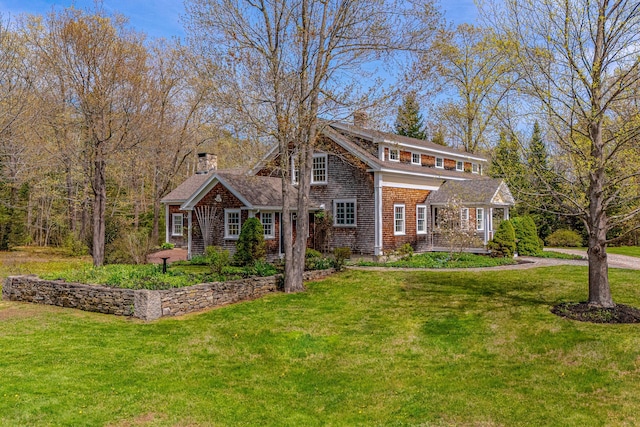 shingle-style home with a chimney and a front lawn