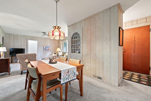 447 Wiscasset Rd, Boothbay, ME 04537 - dining area with light colored carpet, a ceiling fan, and wood walls