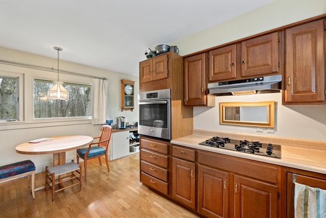 447 Wiscasset Rd, Boothbay, ME 04537 - kitchen with under cabinet range hood, stainless steel oven, black stovetop, and brown cabinets
