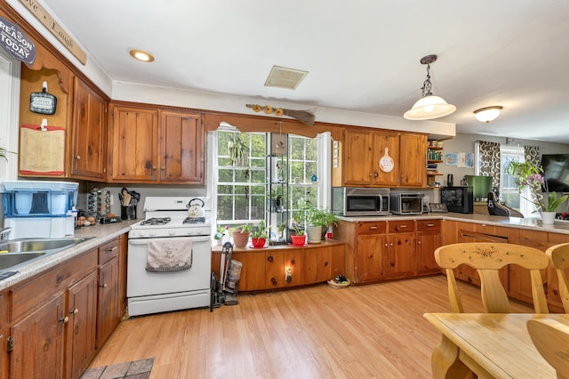 28-30 W Winds Dr, Lebanon, ME 04027 - kitchen with gas range gas stove, stainless steel microwave, brown cabinets, light countertops, and light wood finished floors