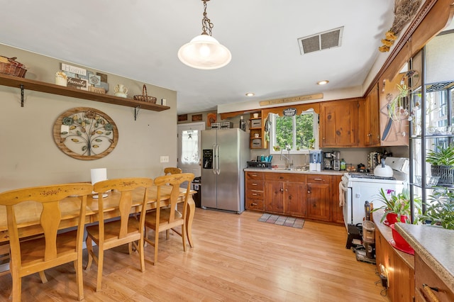 28-30 W Winds Dr, Lebanon, ME 04027 - kitchen with stainless steel fridge with ice dispenser, open shelves, gas range gas stove, brown cabinetry, and light countertops