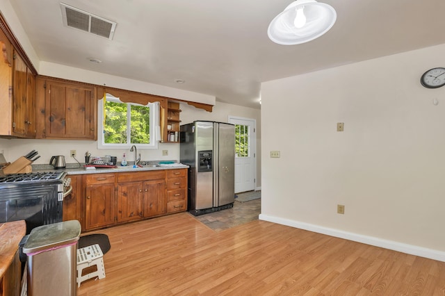 28-30 W Winds Dr, Lebanon, ME 04027 - kitchen featuring stainless steel appliances, light wood-style floors, a sink, brown cabinets, and light countertops