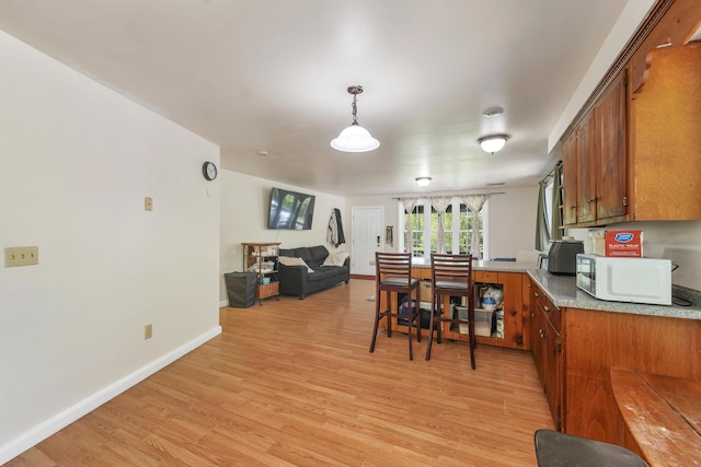28-30 W Winds Dr, Lebanon, ME 04027 - kitchen featuring brown cabinetry, white microwave, light wood-style flooring, and baseboards