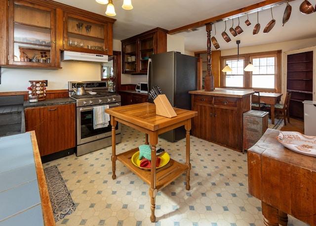 15 Federal St, Bar Harbor, ME 04609 - kitchen with stainless steel appliances, under cabinet range hood, glass insert cabinets, hanging light fixtures, and dark countertops