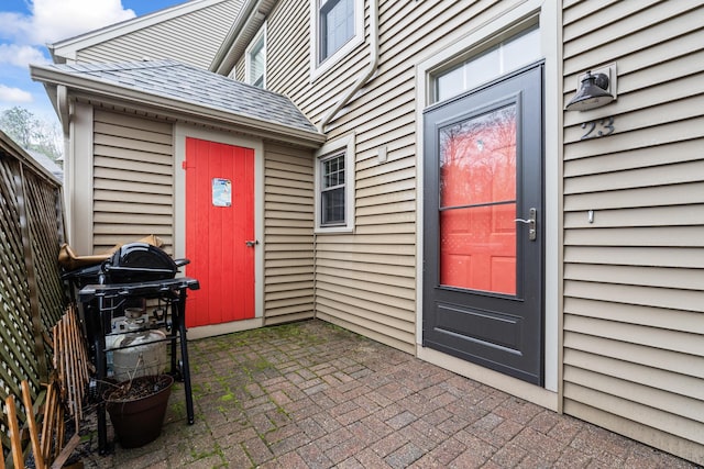 doorway to property featuring roof with shingles and a patio area