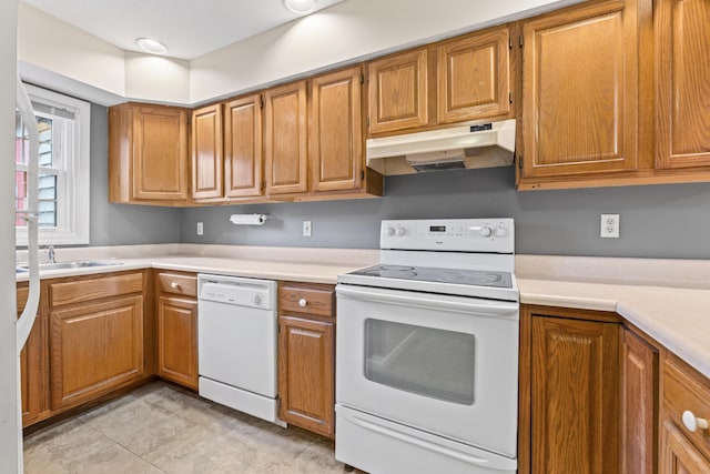 kitchen featuring white appliances, under cabinet range hood, light countertops, and brown cabinets
