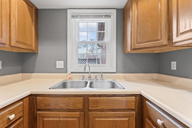 kitchen featuring a sink, light countertops, and brown cabinetry