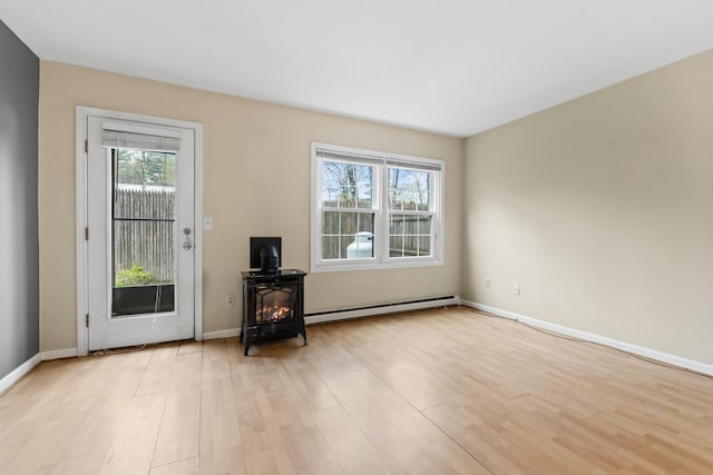 unfurnished living room with a baseboard heating unit, healthy amount of natural light, and light wood finished floors