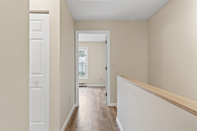 corridor with wood finished floors, baseboards, and a baseboard radiator